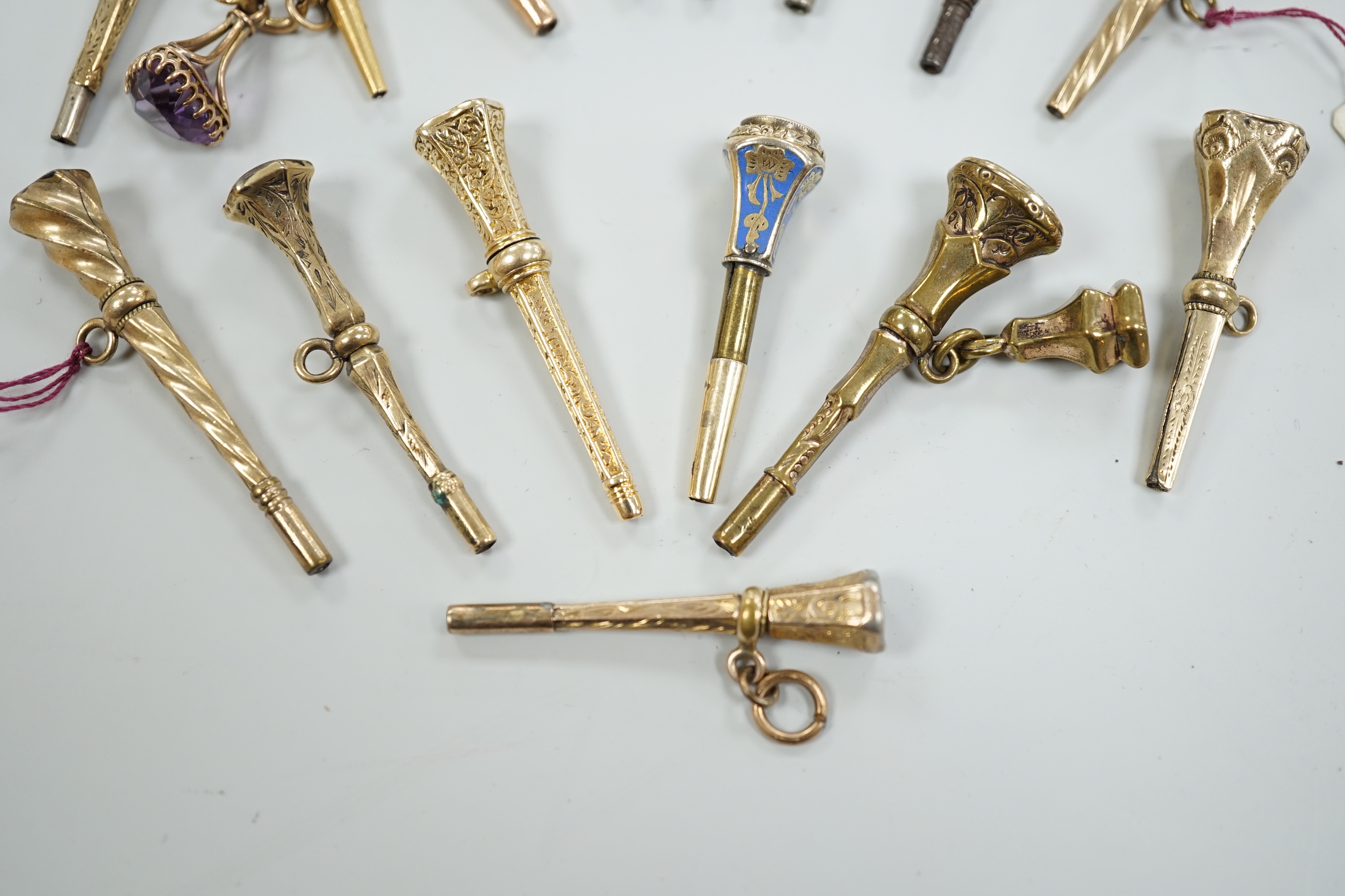 Fifteen assorted 19th century mainly yellow metal overlaid and gem set watch keys, including bloodstone, citrine and white chalcedony and one with enamel, mostly of trumpet form, largest 51mm.